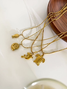 Detail of gold marine life pendants including fish and turtle on textured bead chains
