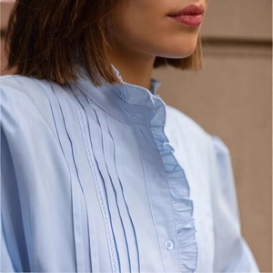 Details einer hellblauen Puffärmeligen Bluse mit Rüschenkragen und Spitzenfalten
