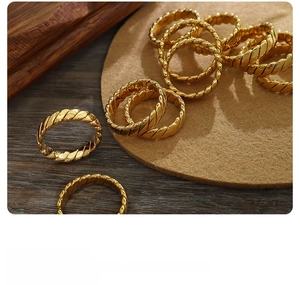 Detail of gold twisted rope rings on a felt mat with a vintage minimalist aesthetic