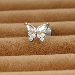Vue macro d'une boucle d'oreille papillon avec gemmes irisées sur plateau en velours