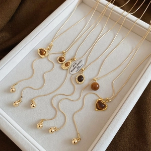 Detail of golden necklaces featuring tiger eye heart pendants on a white jewelry tray