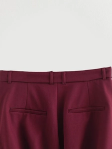 Detailed view of waistband, belt loops and pockets on burgundy tailored trousers