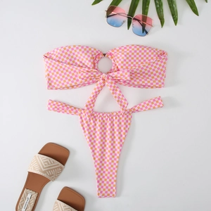 Detailed flat lay of a checkered bandeau bikini with pink pattern and beach accessories