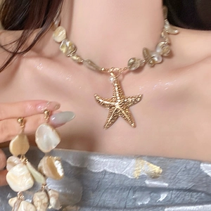 Close-up of golden starfish pendant necklace and matching earrings with faux pearls
