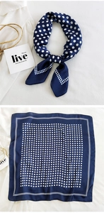Close-up of a navy blue silk-like square scarf with white polka dots and border detail