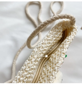 Dettaglio ravvicinato della cerniera liscia e della trama intrecciata della borsa di paglia