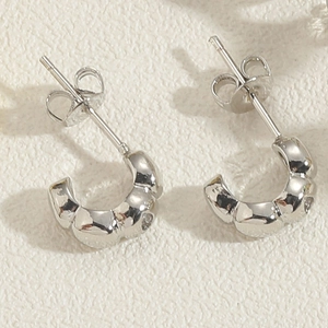 Dettaglio orecchini a C con trama ondulata in rame placcato oro 14K e zirconi brillanti