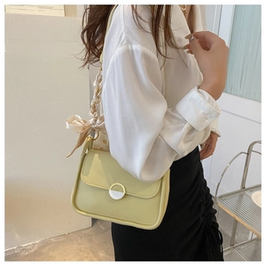 Detail of light yellow leather crossbody bag with metal ring buckle and polka dot scarf