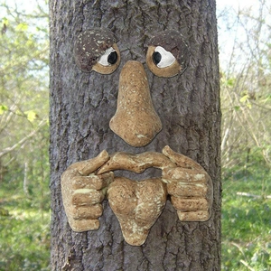 Detailed view of glowing resin tree face features installed on a forest bark surface