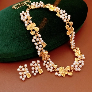 Detail of vintage flower pearl jewelry set featuring leaf motif on green velvet pad