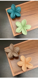 Close-up of four matte resin flower hair claws in forest green, sage, coffee, and beige colors