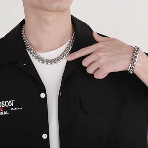 Polished silver cuban link chain set worn by male model on a black shirt background