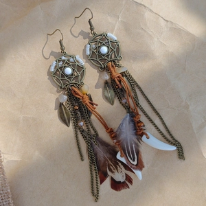 Detail of bohemian feather earrings with bronze dreamcatcher and vintage beads