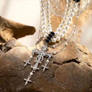 Double-layer pearl necklace with rhinestone crosses on natural rock background