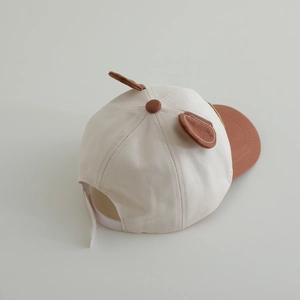 Détail de la casquette bébé avec oreilles d'ours, design bicolore et sangle réglable