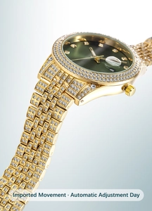 Detail of gold watch with green dial, crystal-encrusted bezel, and luminous calendar window