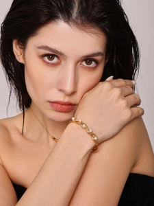 Detail of 18K gold plated C-shaped cuff bracelet with pearls on a model's wrist