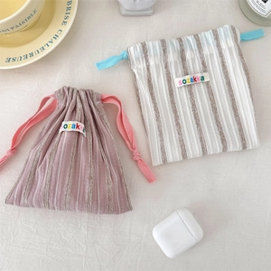 Close-up of striped drawstring storage bags in pink and blue with a woven brand label