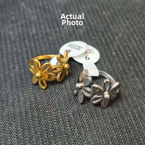 Macro detail of two floral-shaped stainless steel rings with hollow petals in gold and silver