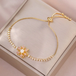 Detail of adjustable gold bracelet with pink flower, pearl center and zircon accents