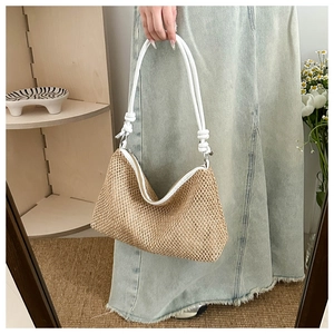 Detail of woven straw handbag with knotted white rope shoulder strap and natural fiber texture