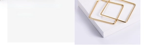 Polished gold square hoop earrings with geometric hollow design on a stone pedestal
