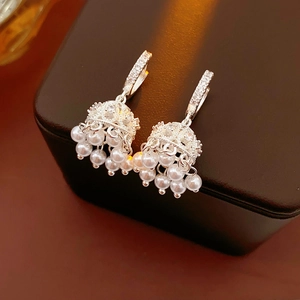 Macro view of silver jhumka earrings with zircon bells and hanging pearls on a jewelry box