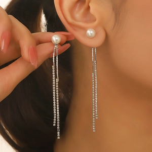 Close-up of elegant long fringe earrings with white pearls and sparkling rhinestone chains