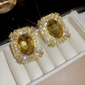 Macro shot of vintage gold earrings with oval yellow gemstone and halo pavé setting