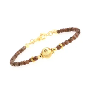 Detailed macro view of faceted brown natural stone beads with a golden textured focal bead