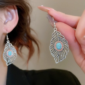 Detailed view of bohemian leaf tassel earrings with turquoise inlay and silver texture