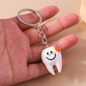 Simpatico portachiavi a forma di dente bianco con faccina sorridente e fiore arancione