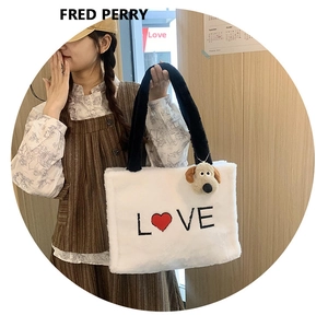 Detail of white plush tote bag featuring LOVE embroidery and cute dog charm attachment