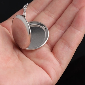 Close-up of an open round silver locket necklace made of polished stainless steel