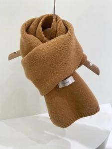 Close-up of soft camel knitted scarf folded neatly on a wooden hanger with logo tag