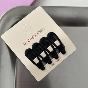 Close-up of four matte black teardrop hair clips on an accessories display card