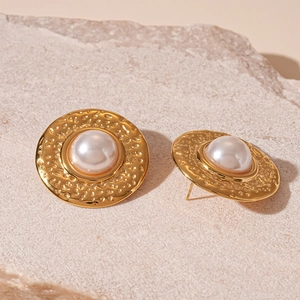 Detail of vintage gold textured metal earrings featuring a central white pearl inlay