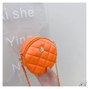 Detailed close-up of orange quilted mini round bag with golden floral hardware and chain