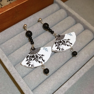Macro detail of Chinese fan drop earrings with bamboo ink pattern on velvet tray