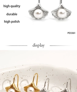 Detail of elegant ginkgo leaf pearl earrings in gold and silver finish for women
