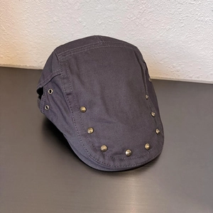 Dettaglio cappello newsboy grigio scuro con rivetti metallici e occhielli traspiranti