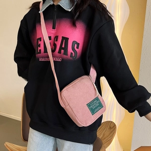 Detailed macro view of pink corduroy texture and green label on stylish crossbody bag