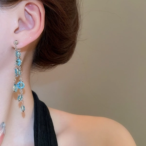 Dettaglio degli orecchini con nappe di cristallo blu e catena d'argento su una modella