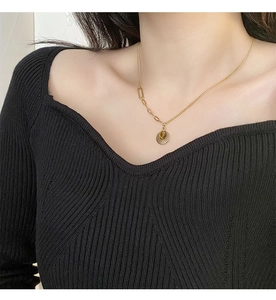 Close-up of golden sunburst pendant necklace with a tiger eye stone on model