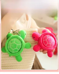Close-up of green and pink plush turtle keychains hanging on a woven bag detail