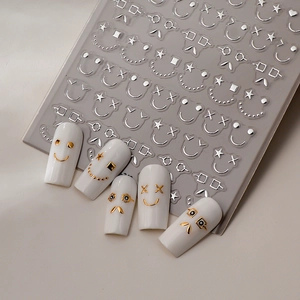 Detail of 3D metallic emoji and star nail stickers applied on white manicured nails