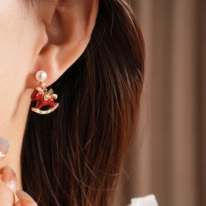 Close-up of elegant red enamel rocking horse earrings with white pearls and gold trim