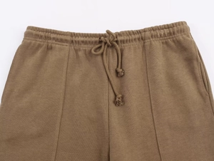 Detail of elastic waistband with drawstring on brown knitted wide-leg lounge trousers