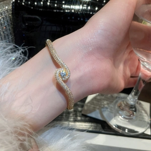 Detail of 18k gold plated wave bangle with sparkling pavé zircon and center stone