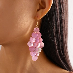 Close-up of pink shell-like layered disc earrings on a model for beach vacation style